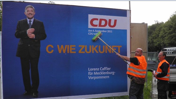 Für den Spruch, den sie plakatieren, können diese beiden Männer nun wirklich nichts.