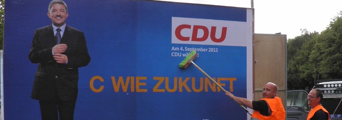 Für den Spruch, den sie plakatieren, können diese beiden Männer nun wirklich nichts.
