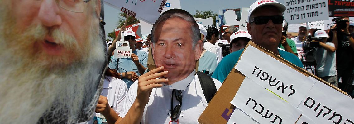 Ein Protestler trägt eine Maske von Netanjahu.