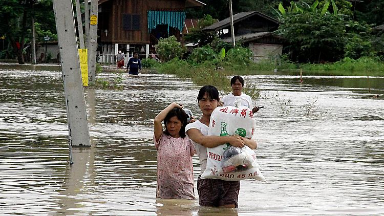 Anwohner waten durch die Fluten im Norden Thailands.