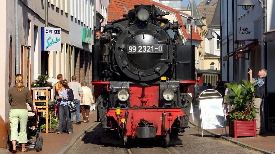 In Bad Doberan dampft ein Zug der Kleinbahn "Molli" durch die engen Straßen.