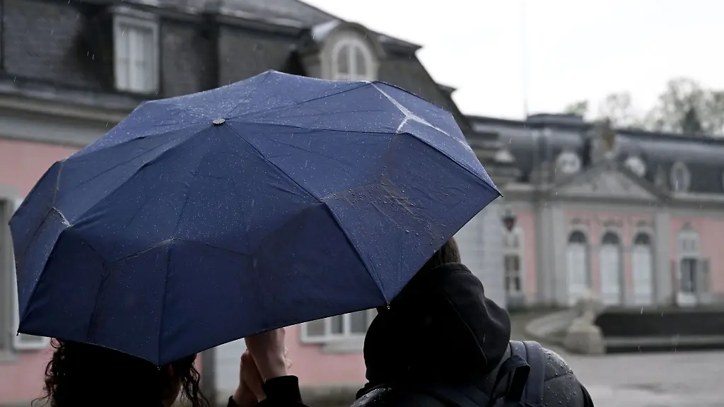 Ein-Mann-und-eine-Frau-blicken-beim-Regenwetter-auf-das-Schloss-Benrath