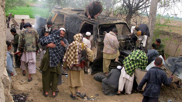 Taliban und afghanische Zivilisten posieren vor dem Wrack des zerstörten Panzerfahrzeugs "Dingo".