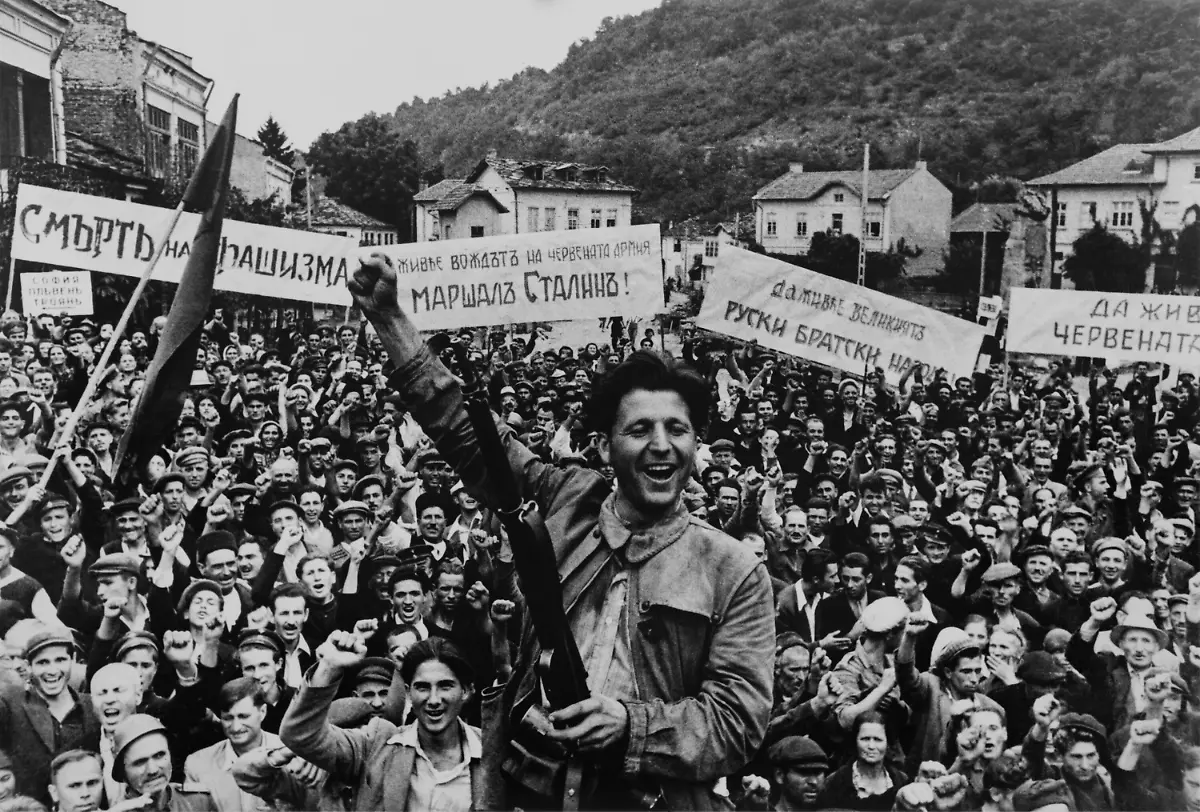 50398289-jpg-Beschreibung-World-War-2-armistice-celebrations-in-Lovech-Bulgaria-Sept-1944-Young-man-in-front-and-the-crowd-make-the-clenched-fist-an-anti-fascist-salute-Signs-in-background-display-slogans-of-Death-to-Fascism-and-Long-live-the-leader-Photo-by-Yevgeny-Khaldei