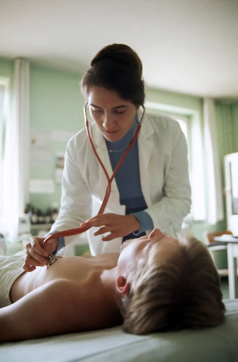 2280835-jpg-Eine-Stabsaerztin-bei-einer-Untersuchung-Fuenf-von-vorerst-fuenfzig-weiblichen-Sanitaetsoffizieren-im-Range-eines-Stabsarztes-der-Bundeswehr-wurden-Anfang-Oktober-1975-von-Bundesverteidigungsminister-Georg-Leber-auf-der-Hardthoehe-in-Bonn-vorgestellt-Sie-sind-ihren-maennlichen-Kollegen-gleichgestellt-bekommen-jedoch-vorerst-keine-Kampfausruestung-Ob-sie-an-Manoevern-teilnehmen-muessen-ist-noch-nicht-entschieden-Die-weiblichen-Sanitaetsoffiziere-sind-nicht-kaserniert-Sie-tragen-blaue-Uniformen-die-von-dem-Modeschoepfer-Heinz-Oestergaard-entworfen-wurden