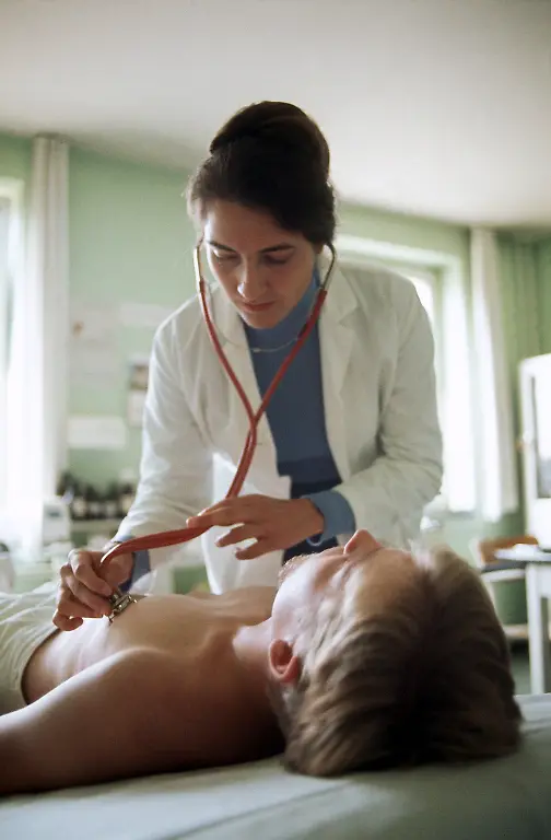 2280835-jpg-Eine-Stabsaerztin-bei-einer-Untersuchung-Fuenf-von-vorerst-fuenfzig-weiblichen-Sanitaetsoffizieren-im-Range-eines-Stabsarztes-der-Bundeswehr-wurden-Anfang-Oktober-1975-von-Bundesverteidigungsminister-Georg-Leber-auf-der-Hardthoehe-in-Bonn-vorgestellt-Sie-sind-ihren-maennlichen-Kollegen-gleichgestellt-bekommen-jedoch-vorerst-keine-Kampfausruestung-Ob-sie-an-Manoevern-teilnehmen-muessen-ist-noch-nicht-entschieden-Die-weiblichen-Sanitaetsoffiziere-sind-nicht-kaserniert-Sie-tragen-blaue-Uniformen-die-von-dem-Modeschoepfer-Heinz-Oestergaard-entworfen-wurden