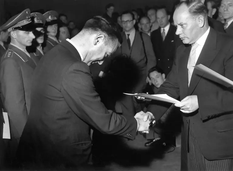 54271060-jpg-Am-12-November-1955-ueberreicht-Bundesverteidigungsminister-Theodor-Blank-r-CDU-in-einer-Kraftfahrzeughalle-der-Ermekeilkaserne-in-Bonn-den-ersten-101-Freiwilligen-der-neuen-deutschen-Streitkraefte-ihre-Ernennungsurkunde-Zwoelf-waren-in-Uniform-erschienen-der-Rest-nahm-die-Urkunde-in-Zivil-entgegen