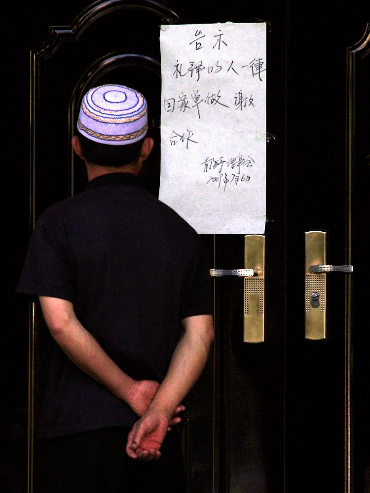 Ein Muslim liest in Ürümqi einen Zettel, der an die Tür einer Moschee gepinnt ist: "Geh nach Hause und bete dort."