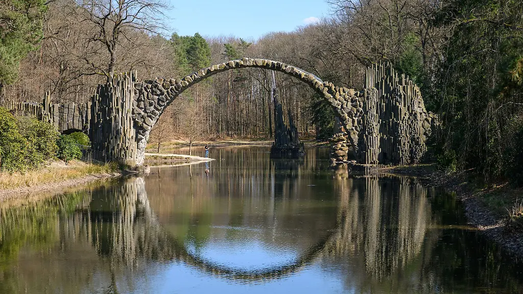 Dank-einer-Spiegelung-im-See-wirkt-die-Rakotzbruecke-wie-ein-Rundbogen
