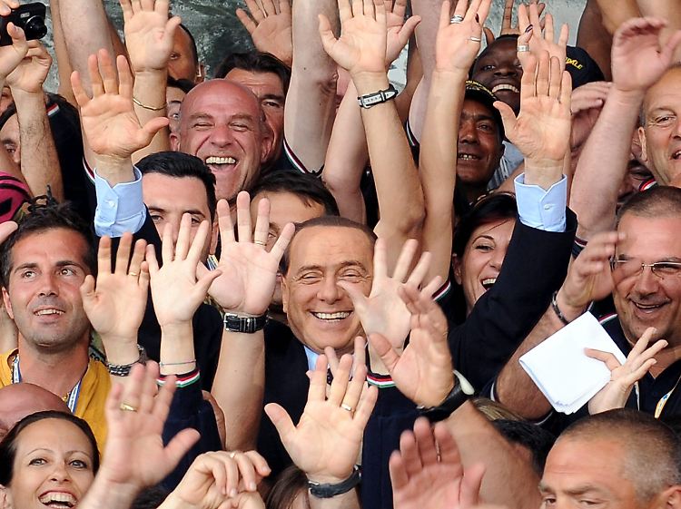 In Umfragewerten auf gleicher Höhe mit Obama: Silvio Berlusconi genießt das Bad in der Menge - wie hier zwischen zahlreichen Freiwilligen, die auf dem G8Gipfel arbeiteten.