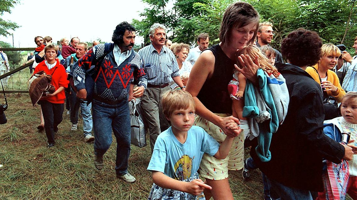 DDR-Flüchtlinge gehen durch ein geöffnetes Grenztor (19. August 1989).