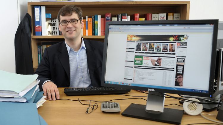 Der Hamburger Medienrechtsanwalt Alexander Wachs in Hamburg an seinem Schreibtisch hinter einem Computermonitor, auf dem die Website eines Download-Portals für Musik und Filme zu sehen ist.