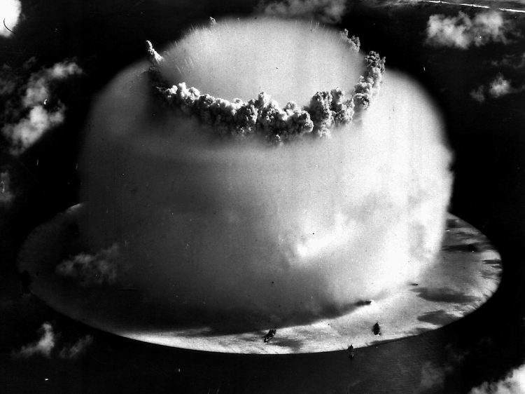 25. Juli 1946: Wieder ein Pilz über dem Bikini-Atoll. Die dunklen Flecke im Vordergrund sind Schiffe, an deren die Zerstörungen beobachtet werden sollten.