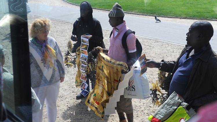 Souvenirverkäufer bieten auf einem Platz in Paris Postkarten und andere Souvenirs.
