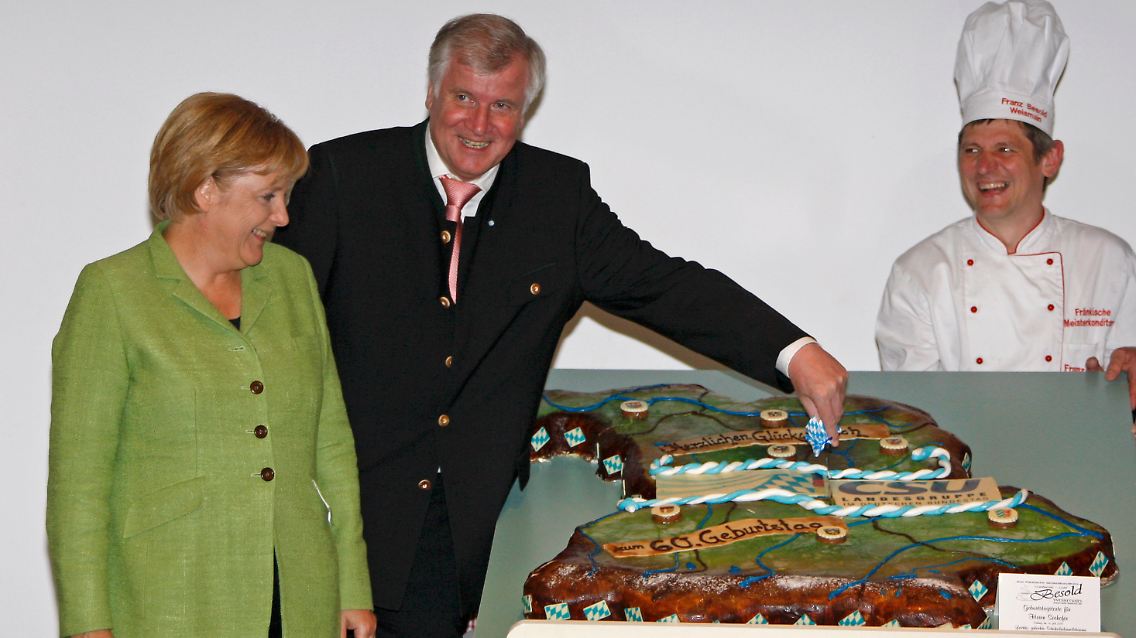 Die Torten-Harmonie täuscht: Die gab's nachträglich zum 60. Geburtstag von Seehofer. Auch die Kanzlerin bekommt ein kleines Stück.