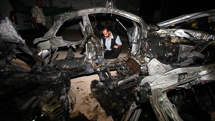Palästinenser untersuchen ein zerstörtes Auto nach einem israelischen Luftangriff.