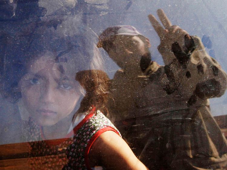 Ein Mädchen flieht vor den Kämpfen in Bani Walid - und wird von einem der Rebellen gegrüßt.