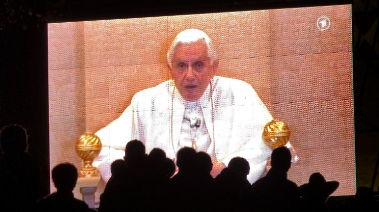 Auch auf Großbildleinwänden verfolgen Menschen, wie der Papst das "Wort zum Sonntag" spricht.