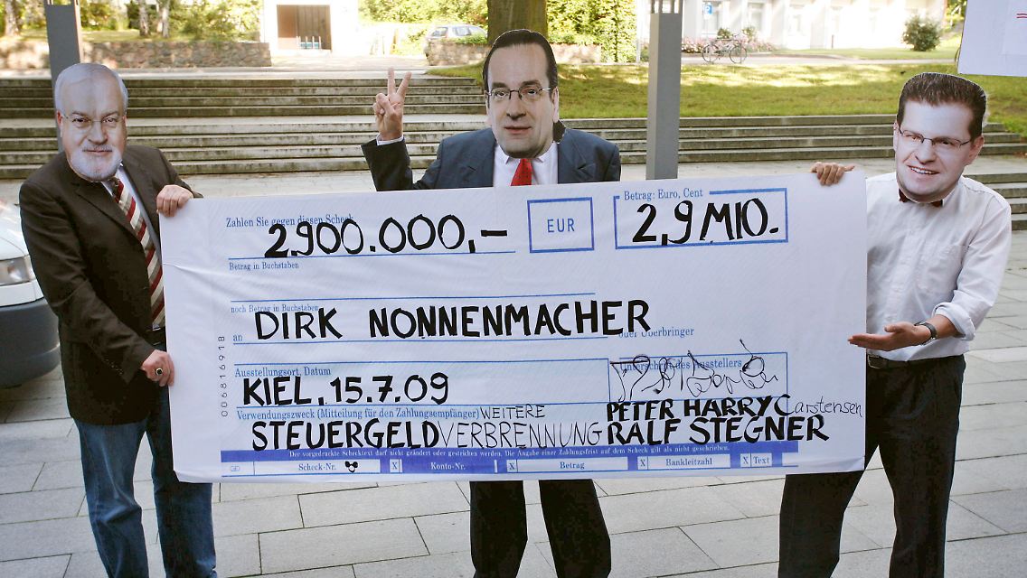 Drei Demonstranten mit Masken von Carstensen, Nonnenmacher und des schleswig-holsteinischen SPD-Landesvorsitzenden Rald Stegner (v.l.) protestieren mit einem überdimensionalen Scheck gegen die Boni-Zahlung.