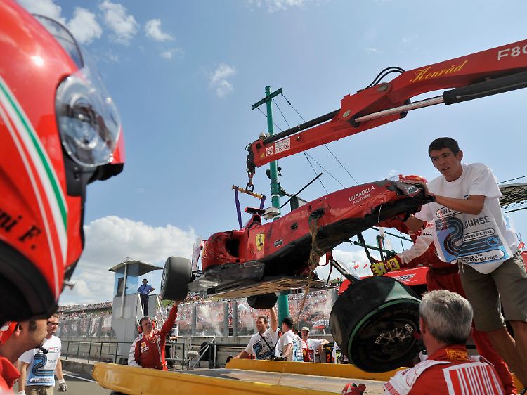 Ein Mitglied der Ferrari-Boxencrew betrachtet das Wrack von Massas Auto.