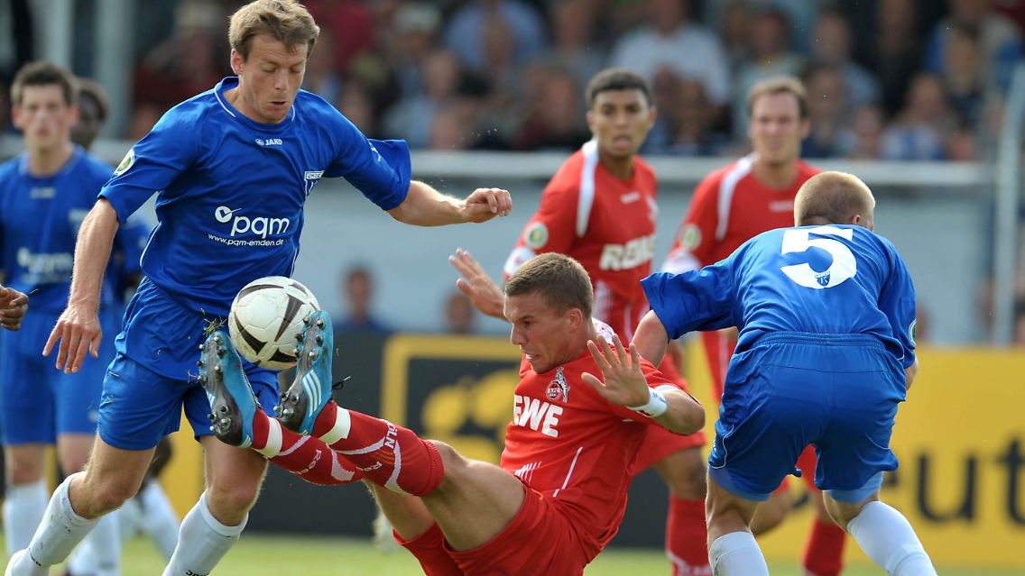 Emdens Arne Janssen, rechts, und Artur Zimmermann kämpfen um den Ball und gegen den Kölner Lukas Podolski.