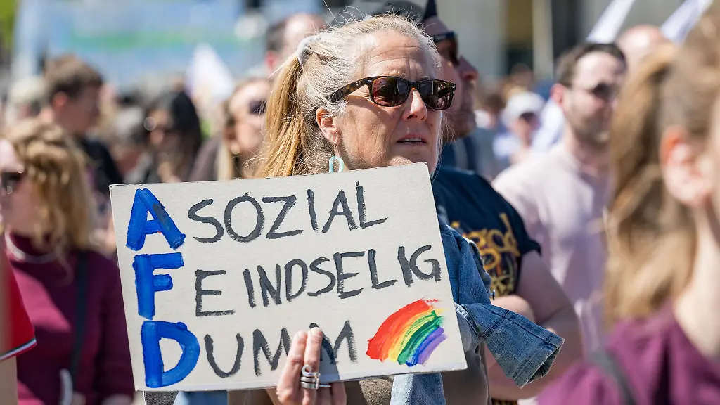 Eine-Demonstrantin-haelt-ein-Plakat-mit-der-Aufschrift-Asozial-Feindselig-Dumm-bei-einer-Demonstration-gegen-die-AfD-in-Muenchen-hoch