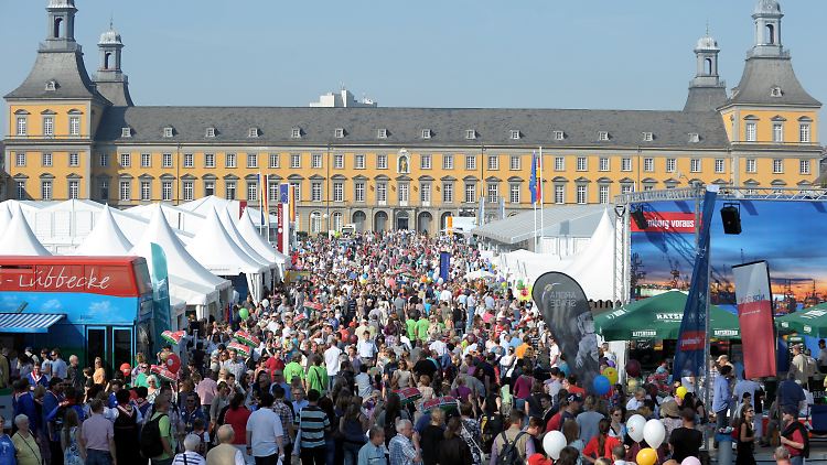 Tausende Besucher des Deutschlandtages gehen in Bonn über die Wiese vor der Universität. 