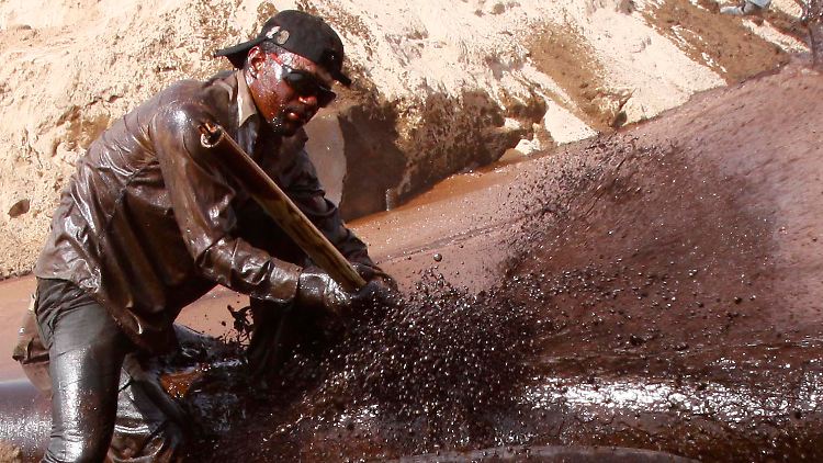 Knietief im Rohöl: Im Irak, südlich von Basra, versucht ein Pipeline-Experte ein Leck in einer mutwillig beschädigten Lieferröhre zu stopfen.