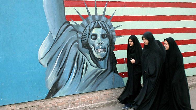 Frauen gehen im Iran an einem anti-amerikanischen Wandbild vorbei.
