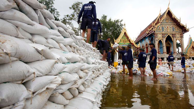 Mit Sandsäcken versuchen Männer in Bangkok, die Wassermassen aufzuhalten.
