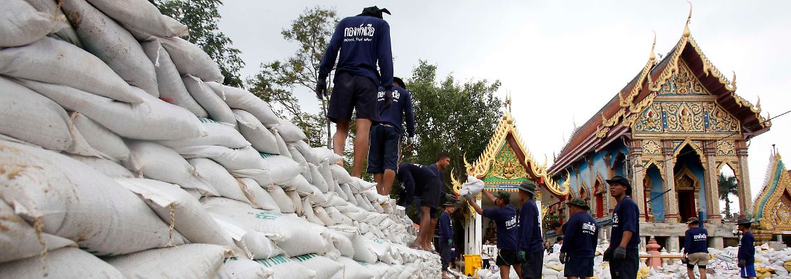 Mit Sandsäcken versuchen Männer in Bangkok, die Wassermassen aufzuhalten.