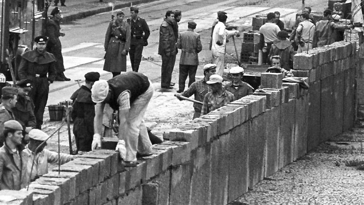Unter der Aufsicht von bewaffneten Volkspolizisten errichtet eine Ostberliner Maurerkolonne am 18. August 1961 an der sowjetisch-amerikanischen Sektorengenze am Potsdamer Platz eine mannshohe Mauer.