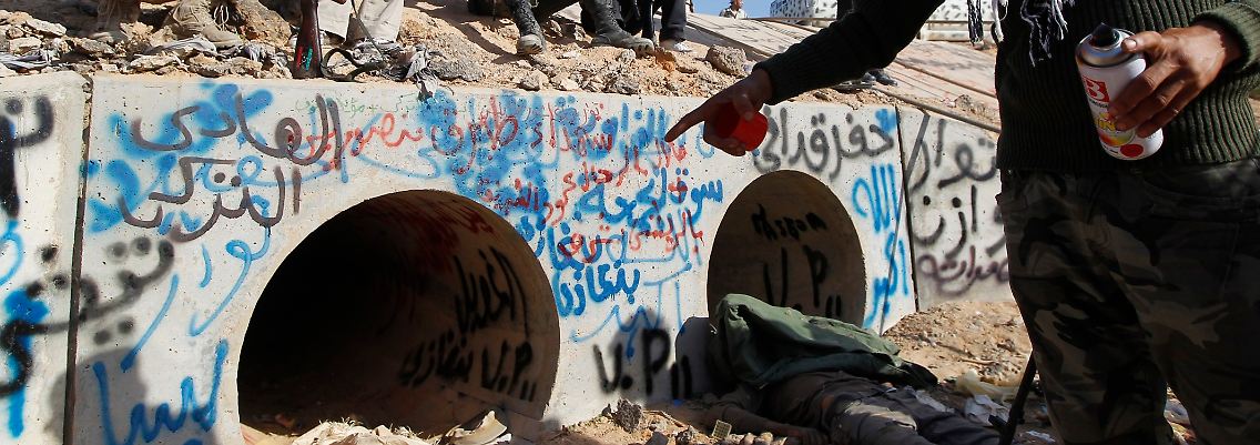 Milizionäre zeigen auf die Röhren, in denen sich Gaddafi versteckt haben soll.