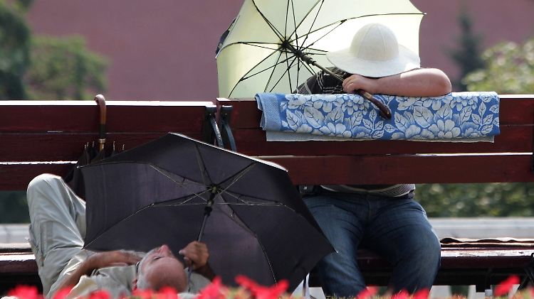 24. Juli 2010: Menschen in Moskau suchen unter Schirmen Schutz vor der Sonne. Die Temperatur betrug dort an diesem Tag bis zu 35 Grad Celsius.