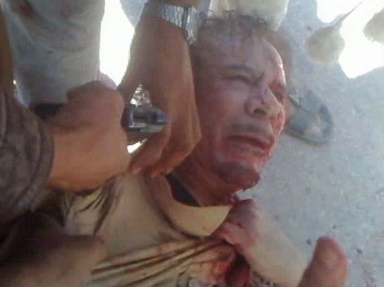 Ein Kämpfer des Übergangsrats hält eine Pistole an den Kopf des noch lebenden Gaddafi - unklar ist, wie der Diktator starb.