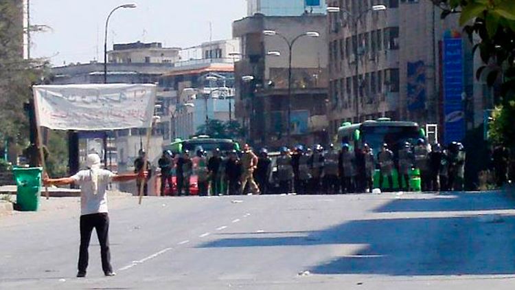 Ein Demonstrant stellt sich in Khalidia nahe Homs vor der Polizei auf.