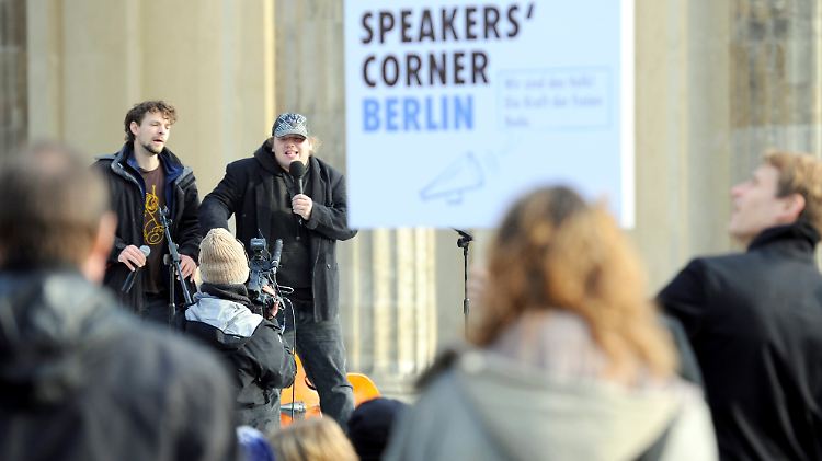 Passanten hören am Brandenburger Tor in Berlin Sprechern zu, die an einer improvisierten "Speakers Corner" reden.