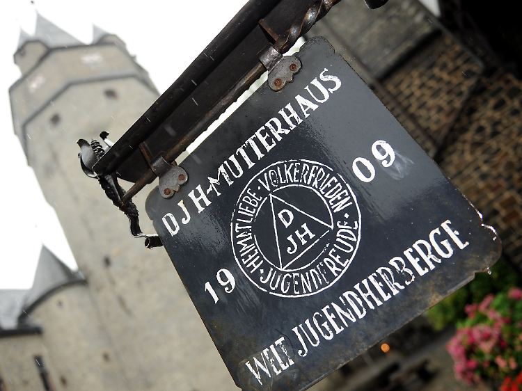 Eine Tafel weist vor dem Bergfried von Burg Altena in Altena auf die erste Jugendherberge hin, die hier 1912 eingerichtet wurde. Hier gründete Richard Schirrmann 1909 das Jugendherbergswerk.
