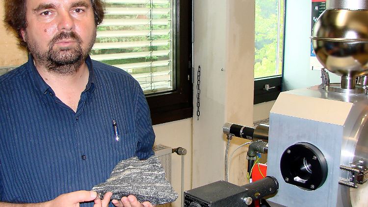 Der Geochemiker Klaus Mezger steht mit einem vier Milliarden Jahre alten Gestein im Institut für Mineralogie der Universität Münster vor einem Massenspektrometer zur Untersuchung von Gesteinsproben.
