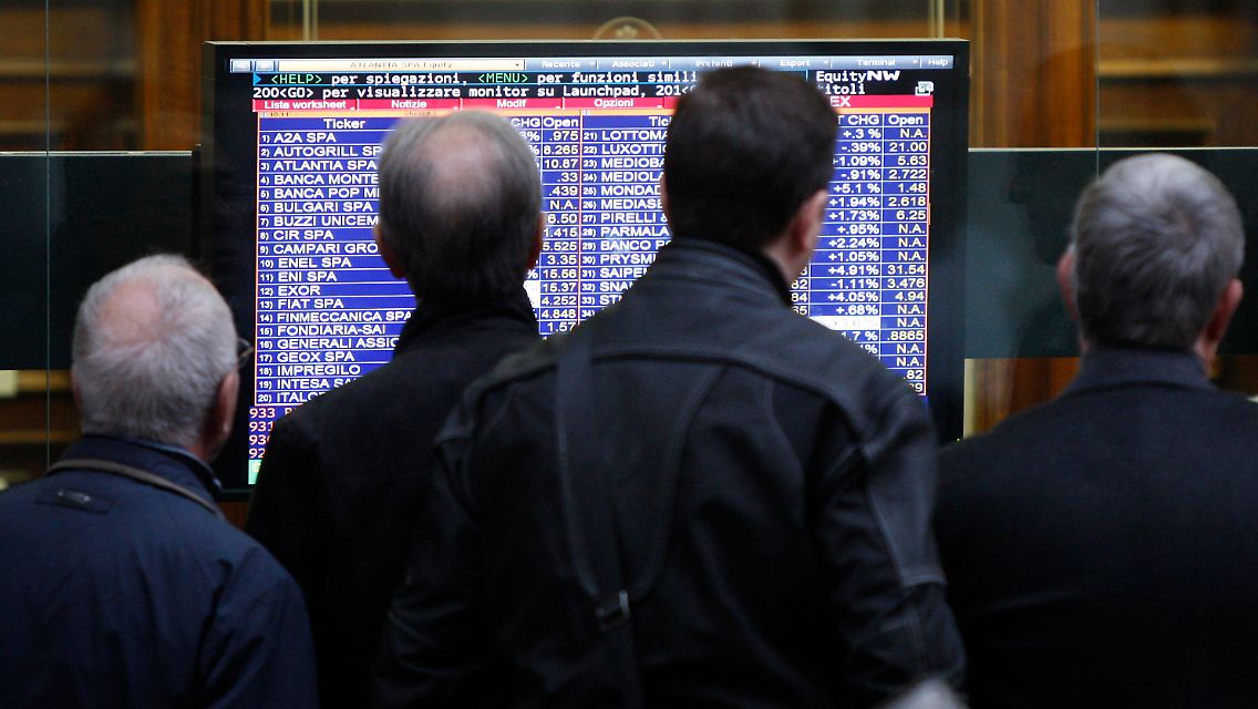 Passanten blicken an der Mailander Börse auf einen Monitor mit Kursinformationen.