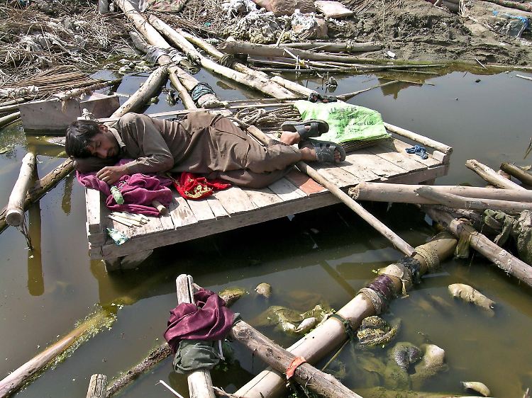 Ein Mann schläft auf den Trümmern seines durch die Fluten zerstörten Hauses in Nowshera, Pakistan.