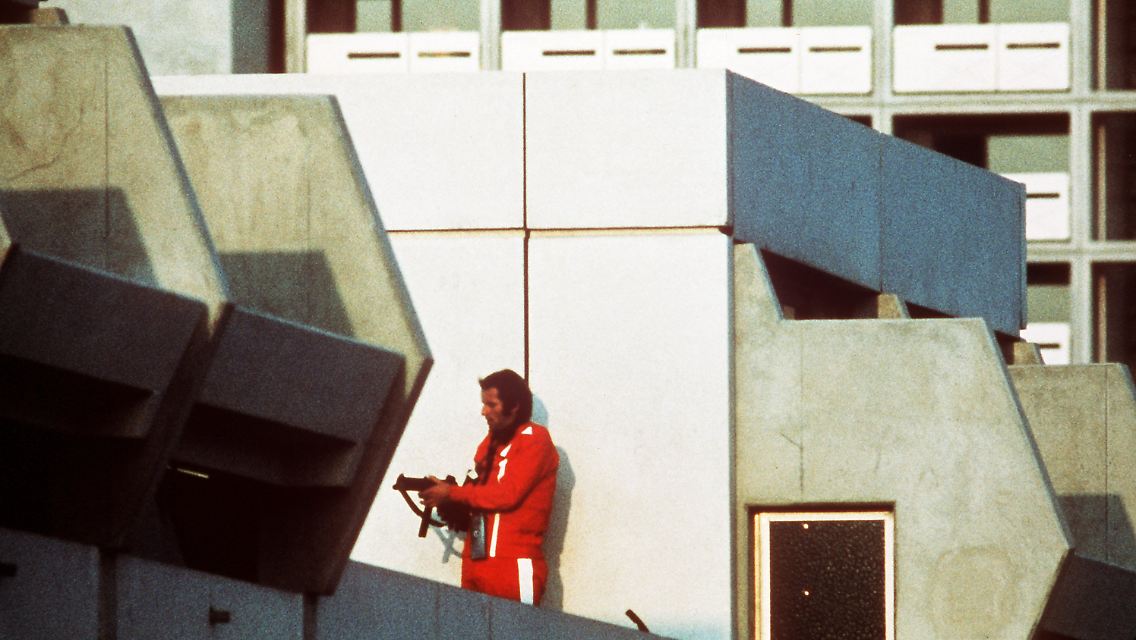 Ein bewaffneter Polizeibeamter im Trainingsanzug sichert am 5. September 1972 im Olympischen Dorf in München den Block, in dem Terroristen die israelischen Geiseln festhalten