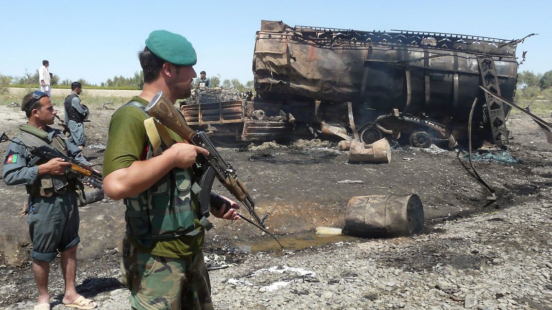 Afghanische Sicherheitskräfte sichern den Ort des Angriff, im Hintergrund ein zerstörter Tanklaster.