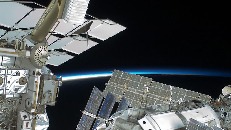 Im Hintergrund der ISS strahlt die blaue Linie der Erdatmosphäre - wie verdreckt Welt und All sind, ist auf diesem Bild nicht zu erkennen.