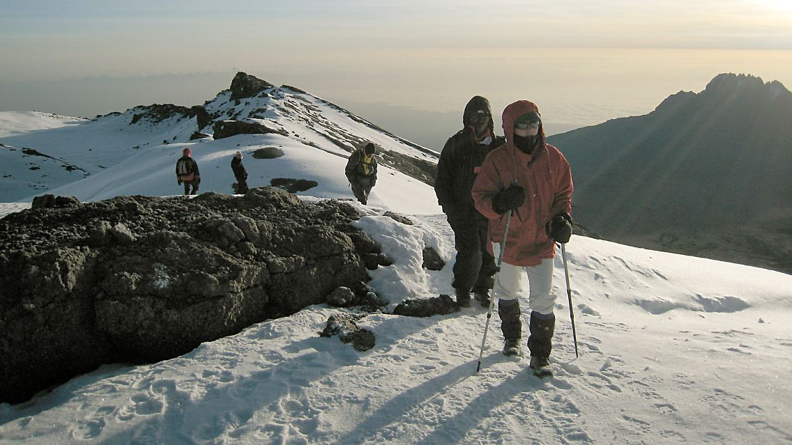 Eine Gruppe Bergsteiger überquert auf dem Weg zum Gipfel des Kilimandscharo ein Schneefeld.