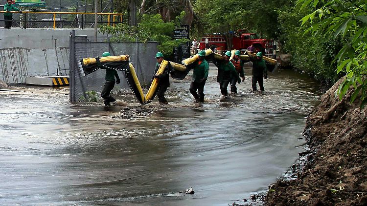 Arbeiter der kolumbianischen Ölgesellschaft waten durch das verseuchte Wasser.