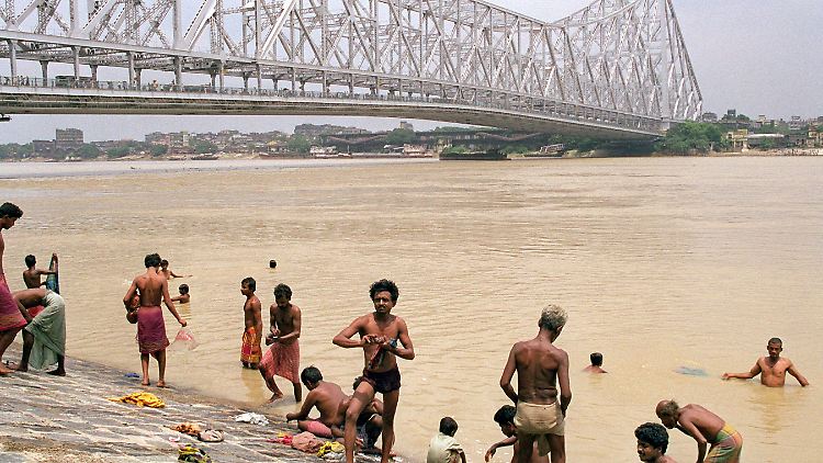 Im Ganges badende Inder vor der Howrah-Brücke in Kalkutta.