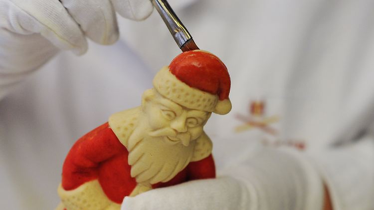 Eine Mitarbeiterin "schminkt" bei Niederegger in Lübeck einen Weihnachtsmann aus Marzipan.