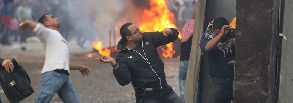 Demonstranten schmeißen Steine auf Beamte der Militärpolizei.