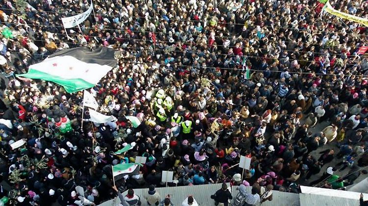 Die Beobachter der Arabischen Liga inmitten der Demonstranten (Männer mit gelben Westen, Bildmitte).